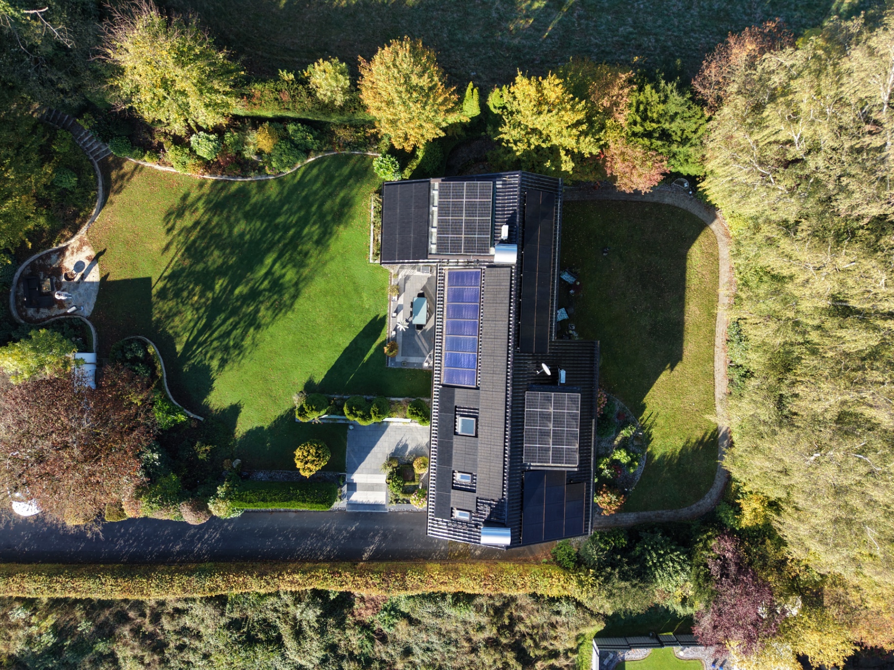 Drohnenaufnahme von oben: Haus mit Photovoltaik auf parkähnlichem Grundstück
